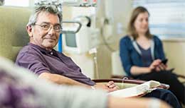 Senior patient sitting on hospital chair, smiling looking at camera
