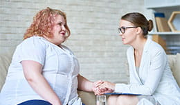 Physician holding hand and discussing with patient with obesity