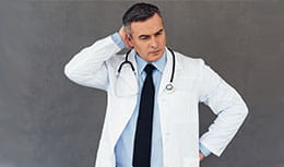 Physician standing by themselves, thinking, holding his head with one hand