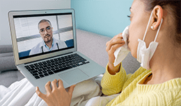 girl, blowing her nose in bed speaking with physician virtually
