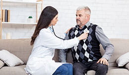 physician checking elder patient's heart with stethoscope