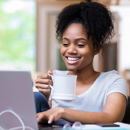 African-American woman on computer with coffee