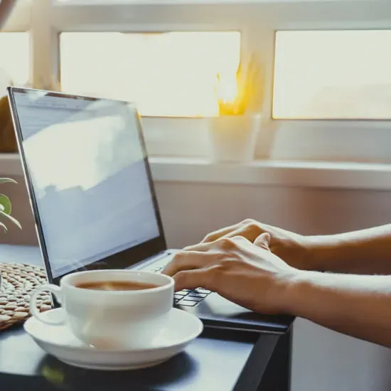Man typing on laptop computer with tea