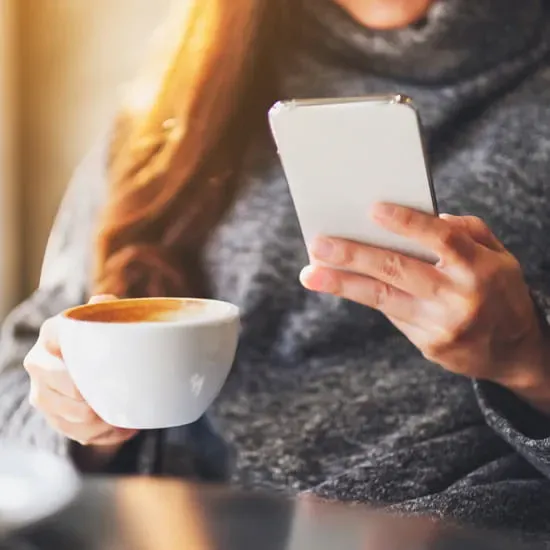 Woman checking phone with coffee