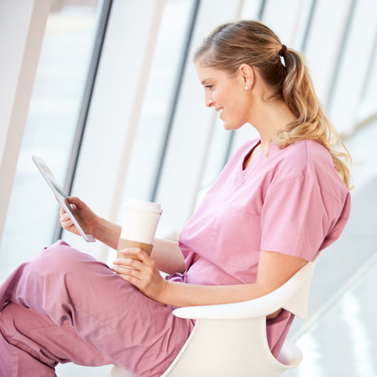 Nurse relaxing with tablet and coffee