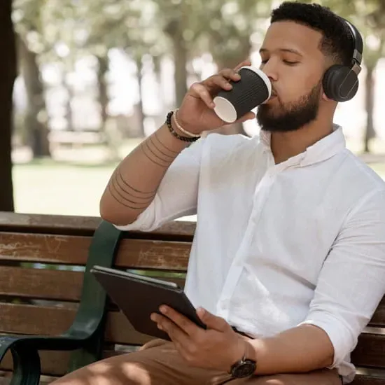African-American man outside with computer tablet and coffee