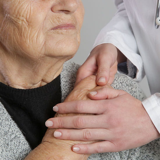 Elderly patient holding doctors hands