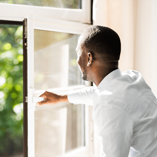Upset young man looking outside window with hand against window