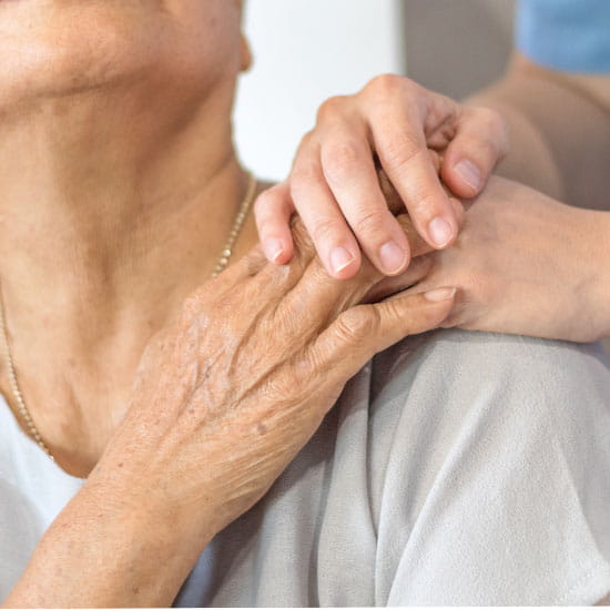 Geriatric doctor holding elders hand to comfort