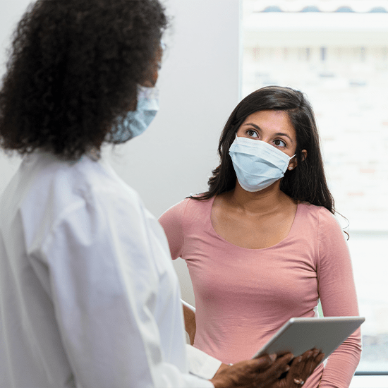 Doctor in protective shield mask talks to obese black woman