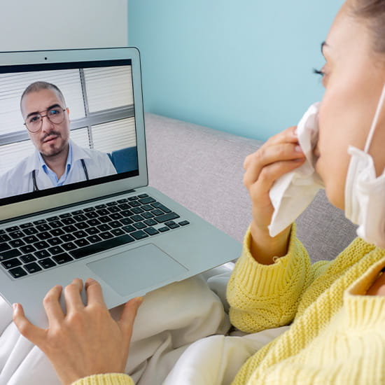 girl, blowing her nose in bed speaking with physician virtually