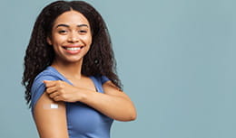 Happy young lady showing vaccinated arm