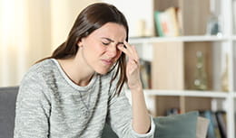 Woman scratching itchy eye at home