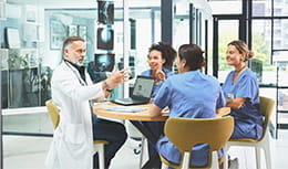 Team of doctors sitting around a circular table having a discussion