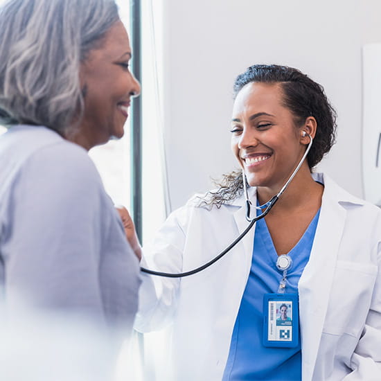 Physician checking elder patient hear with stethoscope
