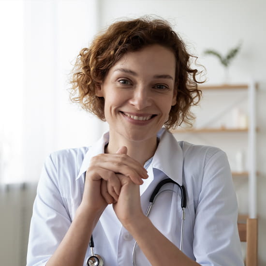 physician sitting on her chair leaning her elbows on a table, smiling contently