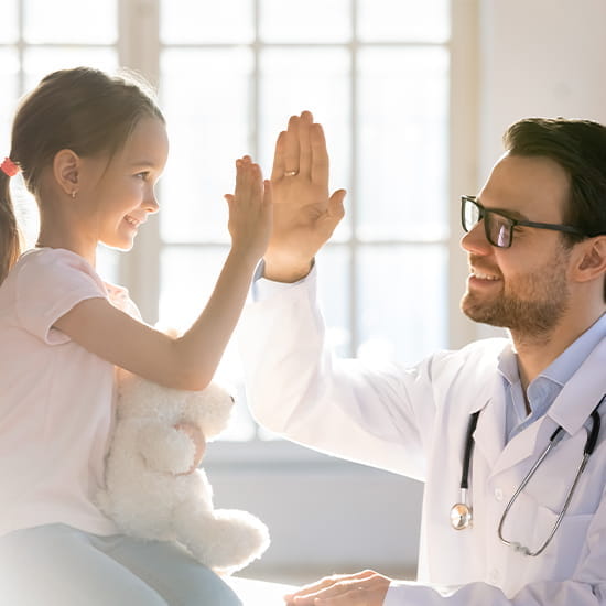 physician giving a high-five to a child girl patient