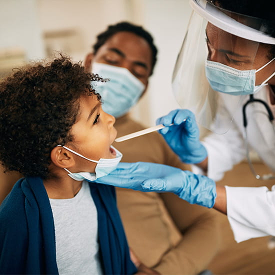 female doctor putting tongue depressor in child's mouth 