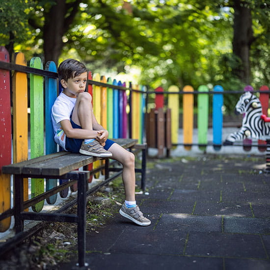 Kid sitting on a bench and feeling lonely