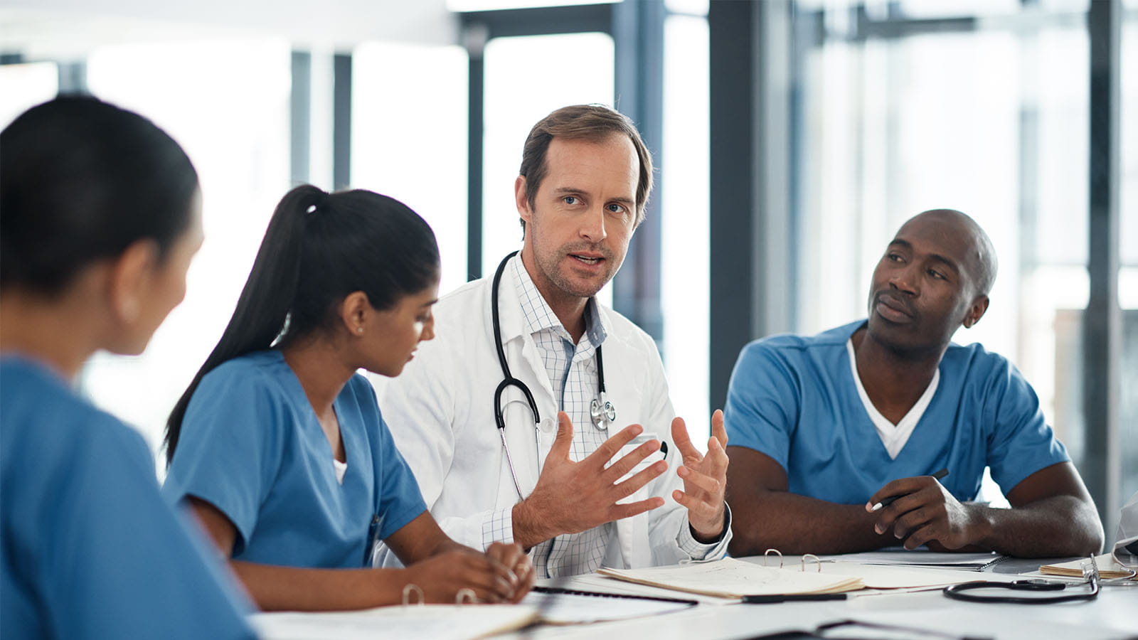 Doctor conversating with nurse team, healthcare professional in medical boardroom office