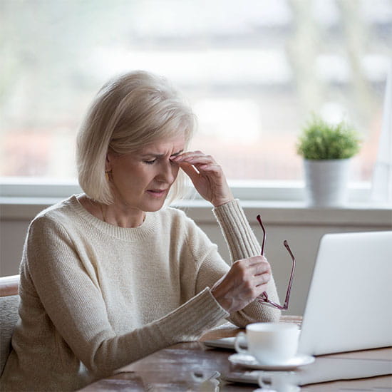Fatigued mature woman taking off glasses suffering from eye strain