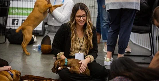 attendee playing with dog at puppy park in exhibit hall