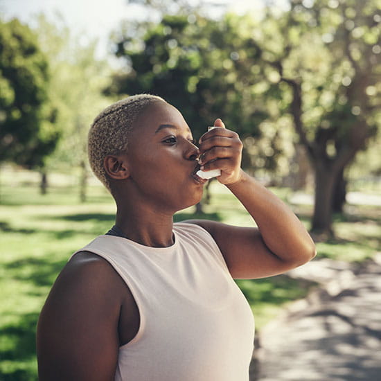 Woman using her inhaler outdoors