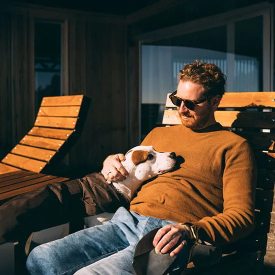 man sitting the sun with his dog