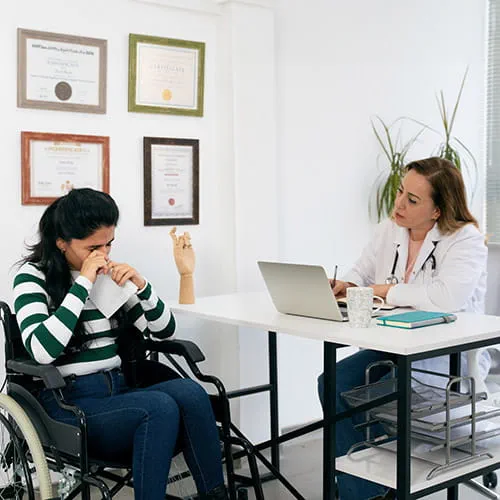 Patient in a wheelchair crying in front of a doctor