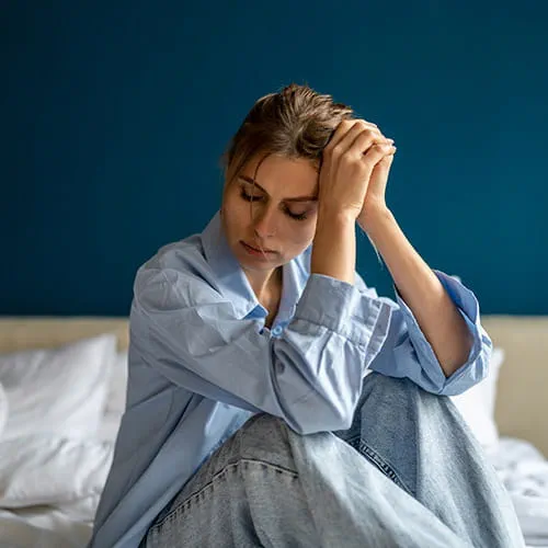 Sad looking woman sitting on a bed
