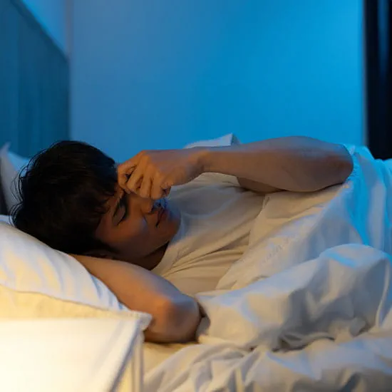 Man holding his face in bed