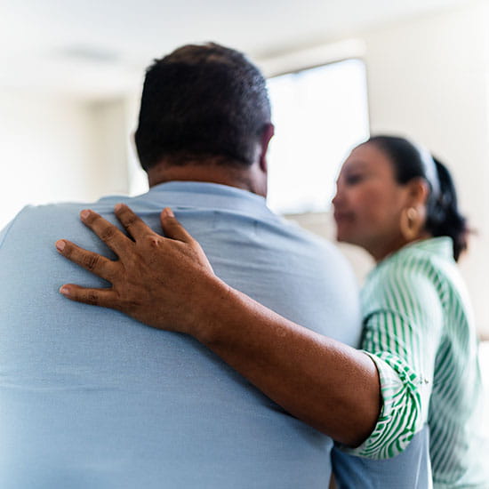 Man being comforted by his wife at home