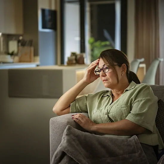 Woman sitting on a couch with hand on her head