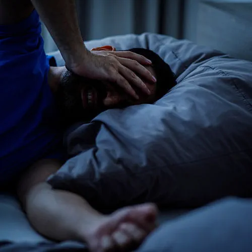 Man in bed with his hand on his head