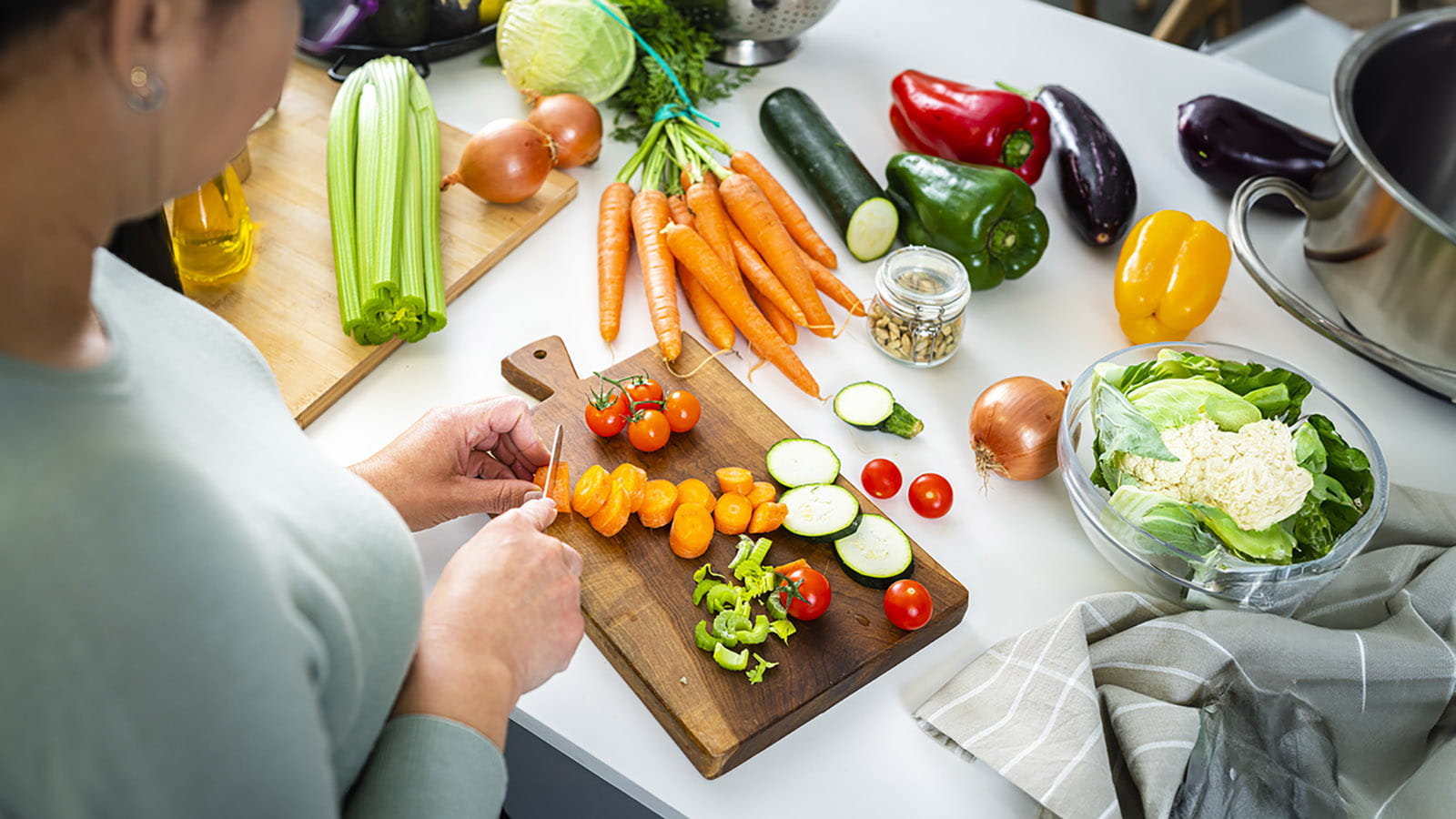 Woman cutting carrots and other vegetables in a kitchen