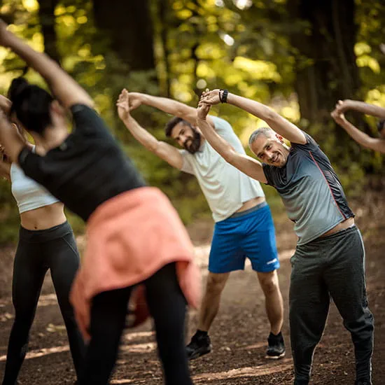 A group of adults stretching in the woods
