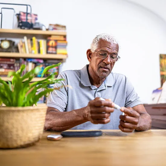 Man checking blood glucose sugar levels on finger at home
