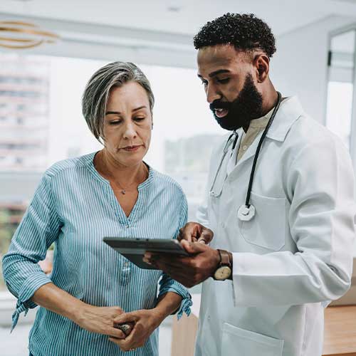 Doctor talking to patient holding digital tablet
