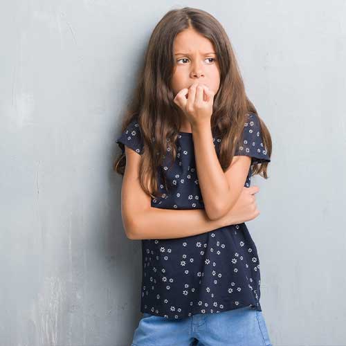 Young hispanic kid over grunge grey wall looking stressed and nervous with hands on mouth biting nails. Anxiety problem.