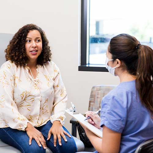 Patient talking with female doctor during a healthcare visit. Mental health professional providing emotional support.