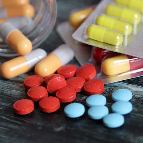 Pills and capsules in blister pack and bottle on dark wooden table, different types of drugs close-up
