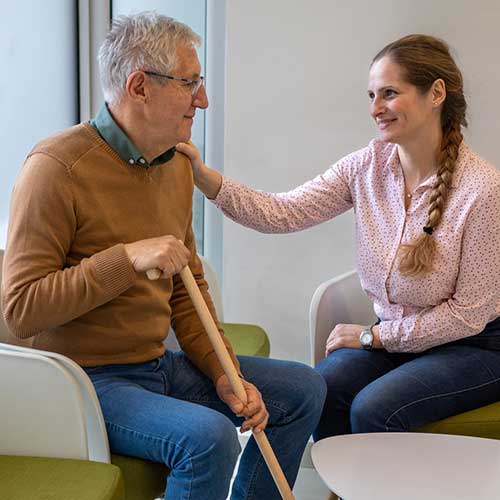 A senior Caucasian man and his mid adult daughter in a medical clinics waiting room