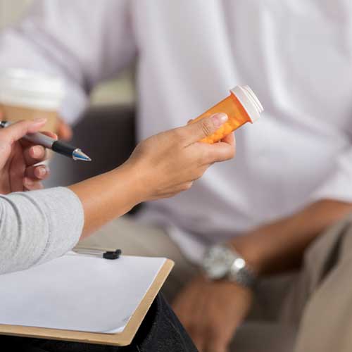Unrecognizable female mental health professional explains to a male patient the side effects of an anti-depressant medication