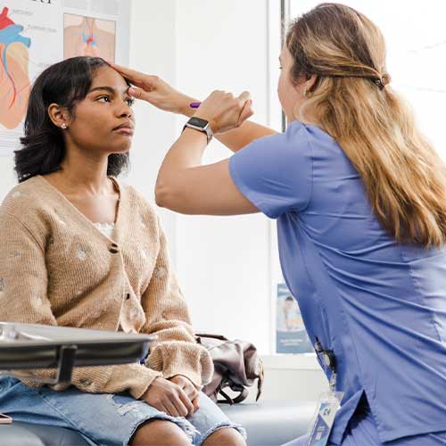 Unrecognizable female doctor checks teen girl's eyes during examination