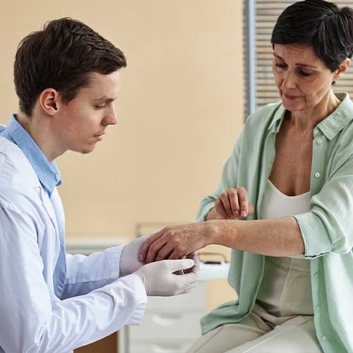 Side view portrait of doctor examining hands of mature woman during consultation in dermatology clinic, copy space