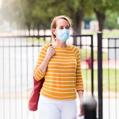Woman wearing face mask walks to business during COVID-19
