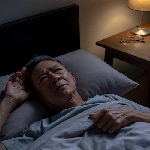 Depressed senior Asian man lying in bed cannot sleep from insomnia