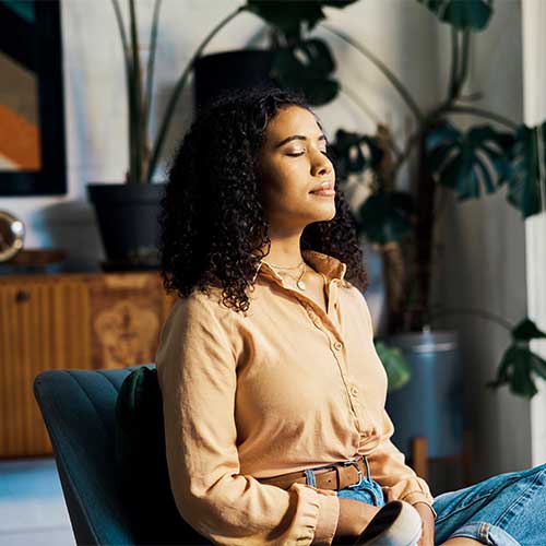 Meditation, calm and african woman sitting alone and feeling mindful and free while doing a breathing exercise for mental health and wellness. Young zen female sitting at home to relax and meditate