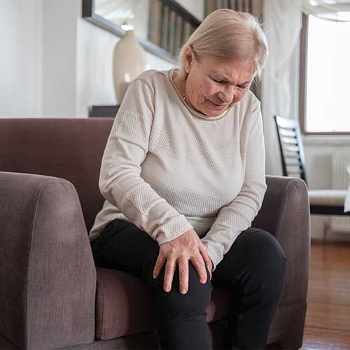 Senior Woman Suffering From Knee Pain At Home