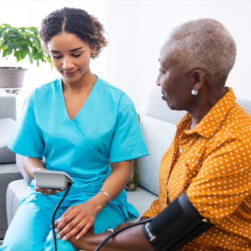 nurse visiting a senior patient at home, measuring her blood pressure
